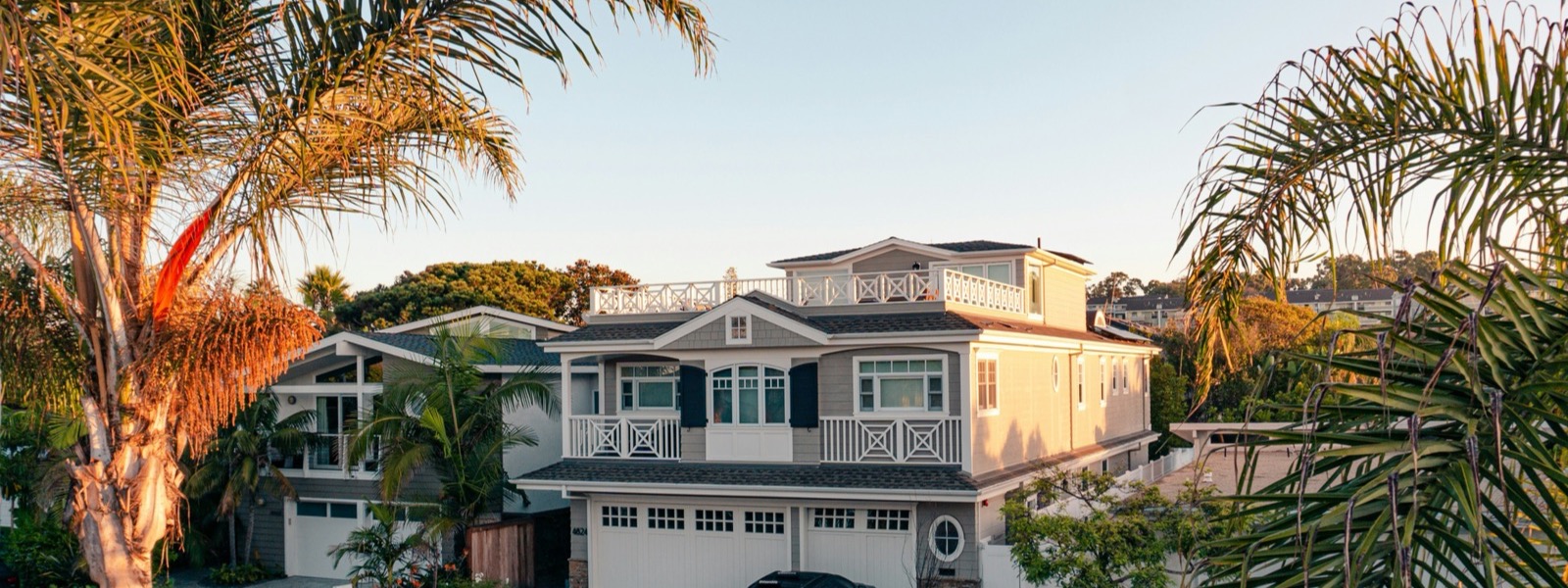 A California home exterior framed by palm trees at sunset